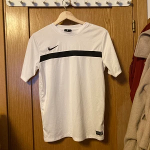 Träings tröja från Nike storlek L (147-158) cm - Jätte fin träningströja i vitt med svarta detaljer från Nike. Tröjan är i jätte bra skick och dessutom helt oanvänd. Storleken är L(147 -158 ), skulle säga att den är lite liten i storlek.