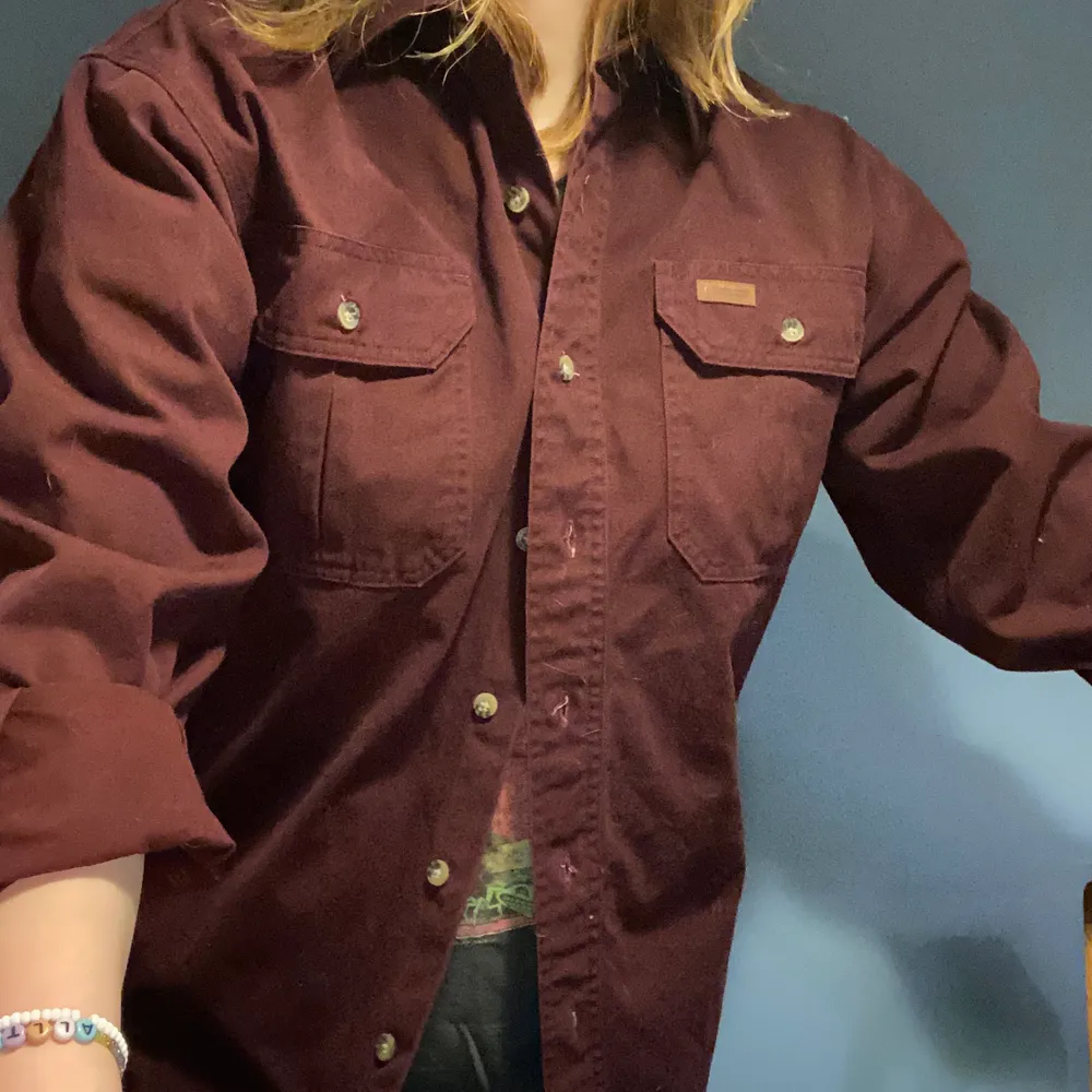 Jättefin vinröd skjorta från carhartt! Den är väldigt tjock så skön att ha på vintern. Passar S-M ✨. Skjortor.