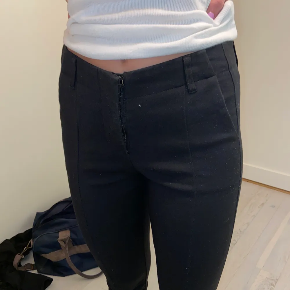 Ett par svarta kostymbyxor med slits och söm längs benen.. Jeans & Byxor.