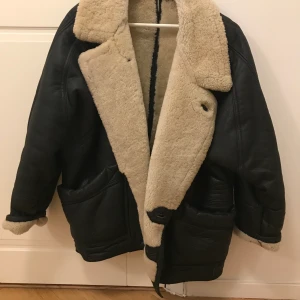48 - En galet snyggt retro pilotjacka. Den är galet varm och mysig och allt är äkta fårskinn och ull. Den har blivit lite sliten på sidan (se bild) och en knapp behövs sys på men det finns en extra i jackan. Storleken är 48, men är väldigt snygg som en oversized jacka ☺️ priset går att diskutera! Möts helst upp då den är svår att frakta 