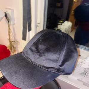 Svart sammets keps - Aldrig använd. Jättefin annars. Den är svart men ser bara blå ut i blixt