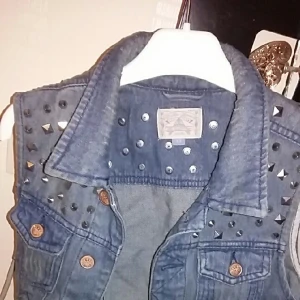  - En jeansväst från "Carlings" med tuffa nitar som detaljer. Passar en XS. Går att ha en lite tjockare tröja under! 

Frakt ingår!