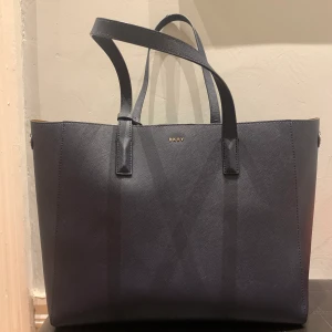 Tote från DKNY mörkblå  - Tote perfekt för jobb / skola med dator. Mörkblå och mörkbrun i. Litet märke i botten( se bild) annars bra skick. 