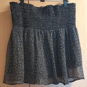 Småprickig kjol strl. M - Kjol från Åhlens storlek M. Kan även användas som topp. Svart med små vita prickar och resårsmock i midjan. Väldigt stretchig så passar upp till XL. Använd någon enstaka gång så bra skick. Pris kan diskuteras. Skickas mot fraktkostnad