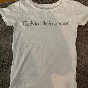 En vit lite tunnare T-shirt från Calvin Klein jeans. Tyget är väldigt tunt och får dörför ett spräckligt mönster i sig. Storlek xs 