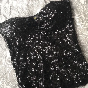 Fest topp - Svart fest topp med paljetter på både fram och baksidan, inbyggda inlägg så behövs ingen bh under! Står ingen storlek på den men skulle säga Small eller liten Medium. Frakt tillkommer