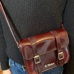 Väska Dr Martens - Vinröd, lackad väska från dr martens! Begagnad skick men fortfarande schysst. Köpt på Dr. Martens, finns inte längre i butik:) köparen står för frakt kan annars mötas upp i Stockholm 💕Buda!! Säljer vid bra bud:)nuvarande: 390