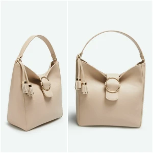 Beige väska Cortefiel - Färg: beige/guld. Strl: Medium.  Mått: 30 x 28 x 14 cm.   Väska från Märket Cortefiel. Kollektion Höst 2020.  Sluts igen m knapp framtill. Innefack finns m dragkedja. Köpt utomlands för 69.99€ motsvarande ca 770kr. Helt Ny!!! Prislappar samt kvitto finns. Avtagbart tassle's medföljer.