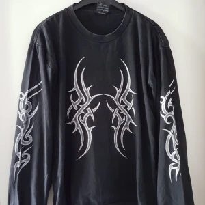  - Vintage svart tröja med coolt tryck. Har ett litet igensytt hål baktill uppe vid ena axeln (se bild 2). Kan skickas om köparen står för fraktkostnaden. 