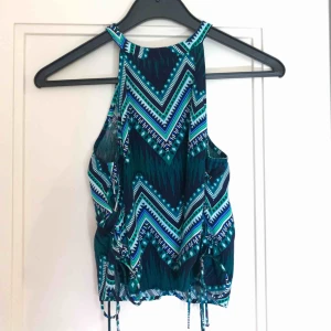 - Mönstrad crop top i blå-grönt. Knapp i nacken. Snörning längst sidorna. Aldrig använd. Köparen står för frakten 💚💙