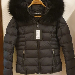 Rock'n blue chill jacka vinterjacka i stl 34. - Rock'n blue chill i stl 34. Passar 32/34. Äkta päls. Jättefint skick! Nypris 3499kr. Lätt och varm. Fram stänger man jackan med en svart dragkedja som man kan dra upp hela vägen över halsen fram, och under dragkedjan sitter det en skyddande knappslå. Jackan har två lätt snedställda sidfickor vilka man stänger med en dragkedja. Huvan går lätt att ta av med en dragkedja och öppningen kan man justera med en spänntamp i framkanten. Pälsbrämet i framkanten, som är äkta svartfärgad tvättbjörn, kan man ta av med små knappar.