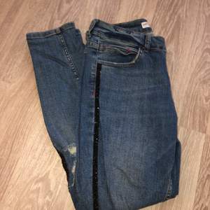 Blåa Zara jeans med slitningsdetaljer och glitterdetalj längst benen. Använda fåtal gånger och i mycket fint skick! Strl 38. 