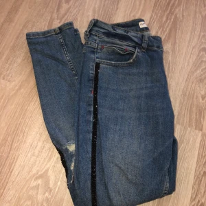 Zara jeans med detaljer  - Blåa Zara jeans med slitningsdetaljer och glitterdetalj längst benen. Använda fåtal gånger och i mycket fint skick! Strl 38. 