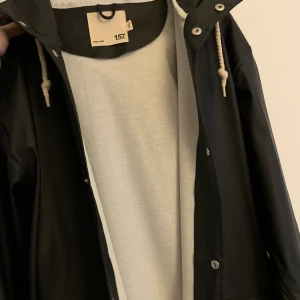 Svart regnbacka L/XL - Jättefin svart regnjacka med luva och stora fickor från lager 157. Storlek L/XL men passar även bra för den som gillar oversize!😍