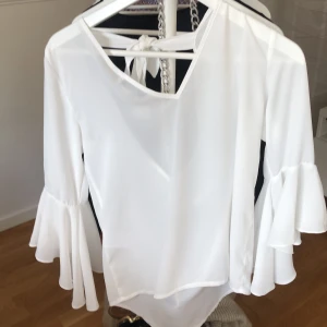Vit blus med vida armar - En vit plus från nakd i storleken 32. Den har vida armar och en fin öppning i bak. Jag har använt den 1 gång så den är i bra skick men den är ganska genomskilning.