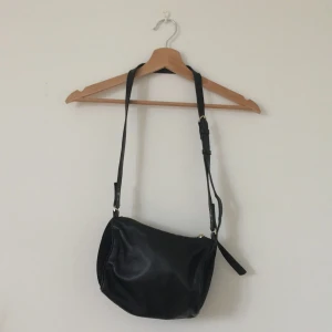 Handväska &Other Stories - Svart handväska i läder från &Other Stories. Har lite av magväske känslan. En del av skaftet till dragkedjan saknas - se bild. Inköpt för 690sek. Frakt ingår 