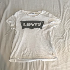 Levi’s t-shirt, strl xs - En vit t-shirt ifrån Levi’s med ett silvrigt/grått print, använt några gånger men utöver det är tröjan i gått skick! Nypris 299kr, du står för frakten🥰