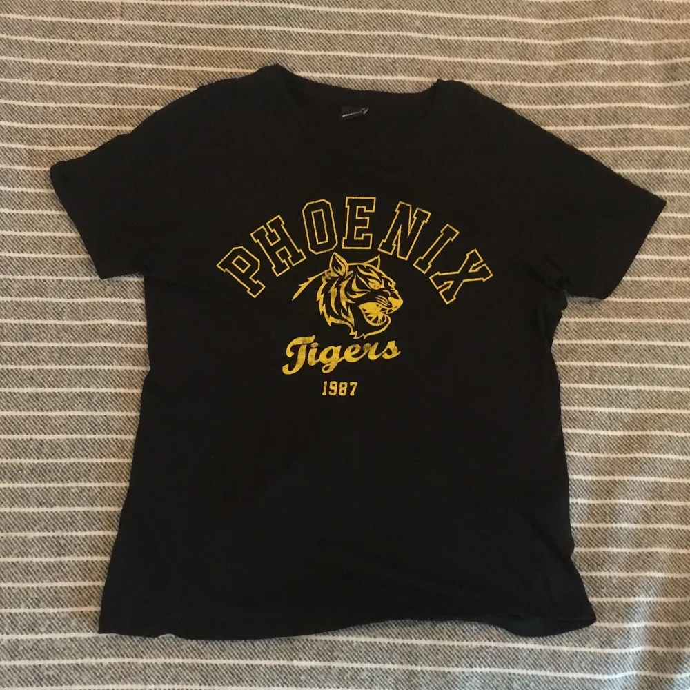 Svart t-Shirt med gult tryck, köpt hos Gina tricot för 3 år sedan använd hyfsat mycket, med bra passform och mycket bra skick. T-shirts.