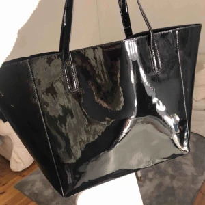 - En fin väska från nelly som jag älskar väldigt mycket men fick två i julklapp och denna är helt oanvänd! Den är ganska stor och rymmer mycket. Materialet är lackimitation tror jag. Frakt tillkommer 💕🥰 Bin 200 men budet just nu 130kr