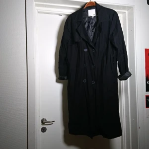 Svart trenchcoat - Stilren svart trenchcoat. Väldigt stilfull modell med snygg skärning. Hölsor för band i midjan (medföljer ej)🌸