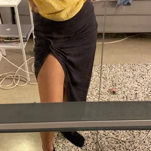 Lång kjol  - Mörkgrå lång kjol med slits på vänstra benet, en ”knytning” vid slitsen.