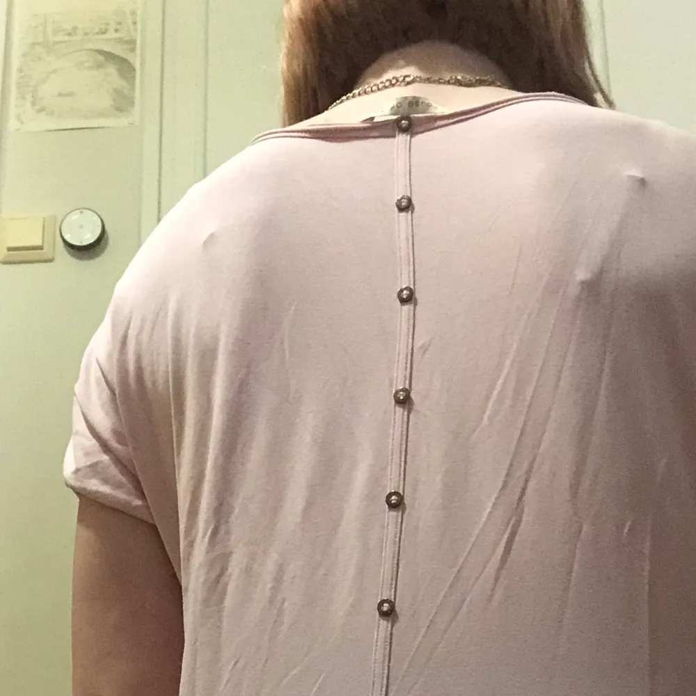 En rosa T-shirt med knappar på ryggen som inte går att knäppa upp. Den är en XL men passar M-XL.. T-shirts.
