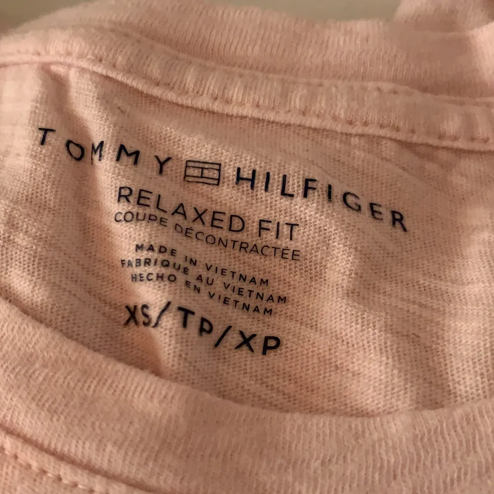 Ljusrosa t-shirt med blå text där det står ”Tommy Hilfiger” med märket på. Äkta och köpt från Tommy Hilfiger, knappt använd! Storlek XS.. T-shirts.