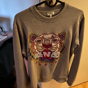Kenzo tröja - Säljer en grå kenzo tröja i storlek XS men passar perfekt på dom som har S och ibland medium, oversize/stor passform. Köptes för 2200 kr använt den få gånger, nyskick.