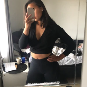 Svart croptop - Svart ribbad crop-top med wrap på framsidan, otroligt skönt material, aldrig använd. Pris kan diskuteras, köpare betalar frakt (måste bort annars skänks den )
