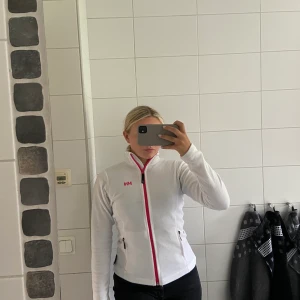 Helly Hansen fleecetröja - Snygg fleecetröja från Helly Hansen, vit med rosa dragkedja och märke. Storlek XS men passar också S, frakt tillkommer✨