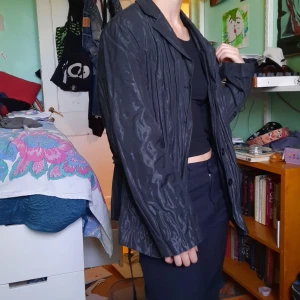 Svart jacka - Svart tunn jacka i som glänser i solen men är matt utan direkt ljus. Band som går att knyta i samma material. Två fickor. Typ vattentät. Min favvo förut!!