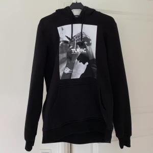 2pac Hoodie svart - Svart hoodie med 2pac tryck ifrån Urban Classics, köpt på Junkyard. Storlek small i unisex storlek. Mycket fint skick med inga skador. Ifall flera intresserade kör jag budgivning. Originalpris: 600 kr Fraktavgiften, 63 kr, står köparen för!💫