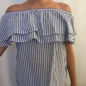 Randig off-shoulder  - Säljer denna trendiga off-shoulder topp från GinaTricot med volanger. Ganska så normal till stor i storleken. Säljes pga flytt 🥰