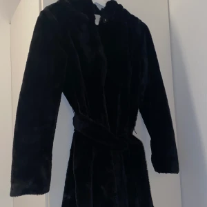 Fuskpäls jacka  - Fuskpälsjacka med luva från vila, bälte finns till. Superskönt och i nyskick! Strl 34