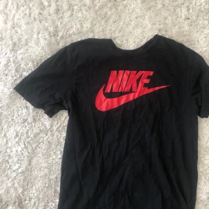 Nike T-shirt M - Svart T-shirt med rött tryck. 