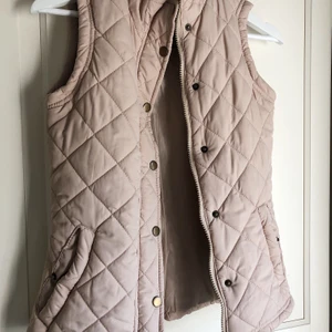 Quiltad väst - Beige, quiltad väst med mörka knappar och dragkedjor. Älskar denna, men använder den aldrig och därför åker den upp här. Storlek 6, vilket motsvarar XS/S. 