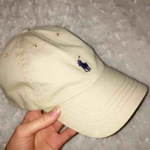  - Skitsnygg beige keps från Ralph Lauren. Använd några gånger men är i väldigt fint skick utan några fläckar. Den har ett justerbart band och passar därför bra till alla olika huvudstorlekar.   Köparen får stå för eventuell frakt💕