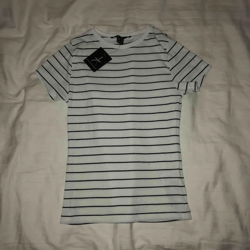 Vit t-shirt med svarta ränder från Primark , aldrig använd bara testad, en liten blå tråd är på tröjan som man ser på bild nr 3, men är ingenting som syns mycket. (Köparen står för frakten). T-shirts.