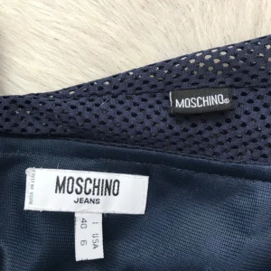  - Set med linne och kjol från Moschino, spetsdetaljer och lätt genomskinlig top med djup rygg