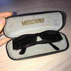 Snygga solglasögon från Moschino i en väldigt mörkröd, nästan svart, färg. Glasen är lite tonade i blått. Har inte kommit till användning. Begagnat fint skick