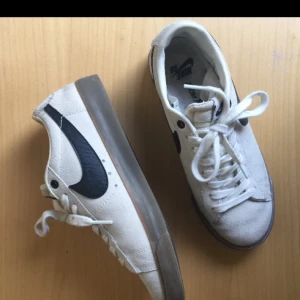  - Vita Nike SB Blazer low sneakers. Storlek 38,5 motsvarar 5,5 i UK storlek. Skorna är i mocka och har en brun gummisula. Knappt använda.