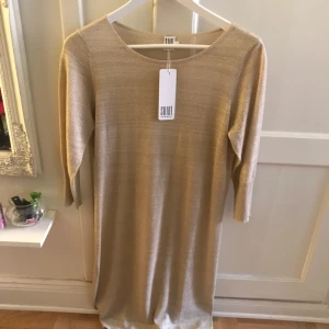  - Helt ny, lapp kvar. Guldaktig klänning