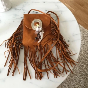  - Jätte fin (fusk mocka) väska med fransar! I mitten sitter ett silver smycke med fjädrar! Frakten ingår