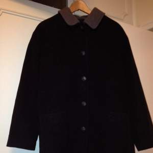 Sparsamt använd svartgrå kappa i cashmere och ull. 