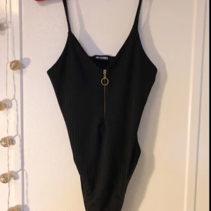 - Svart body i ribbat tyg med knäppning och guldig dragkedja fram. Från Missguided i storlek 36 (passar säkert också M). Använd endast en gång. 40 kr + ev. fraktkostnad via Swish