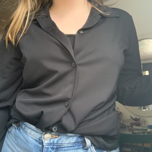 Lång kappa/skjorta! - En lång svart skjorta/kappa. Går att soppa in utan problem då den är så pass tunn, därmed funkar den som blus. Funkar också som kappa till sommarkvällarna t.ex. Storlek L. Fri frakt!