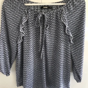 Gullig blus  - Blå mönstrad blus med volanger. Frakt tillkommer! 