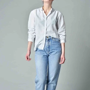 Den vita blusen - En flortunn blus från Cacharel. Rynkor vid ok fram, motveck bak och nätt rund krage. 100% polyester. 30C. 