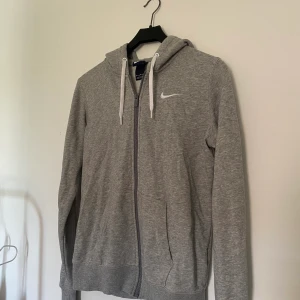 Nike hoodie strl M - Grå hoodie med vita detaljer, storlek M men känns mer som en S, den är liten i storleken. 