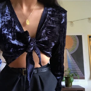 Blå sammetstopp   - Mörkblå topp i krossad immitationssammet. Toppen har något vidare ärmar och knyts framtill. Behöver ej knytas som på bilden. Köpt second hand men aldrig använd. I gott skick! 